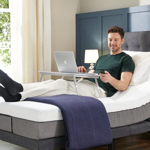 Person sleeping peacefully on an electric adjustable bed with head elevated in a calm neutral-toned bedroom