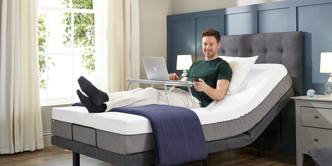 Person sleeping peacefully on an electric adjustable bed with head elevated in a calm neutral-toned bedroom